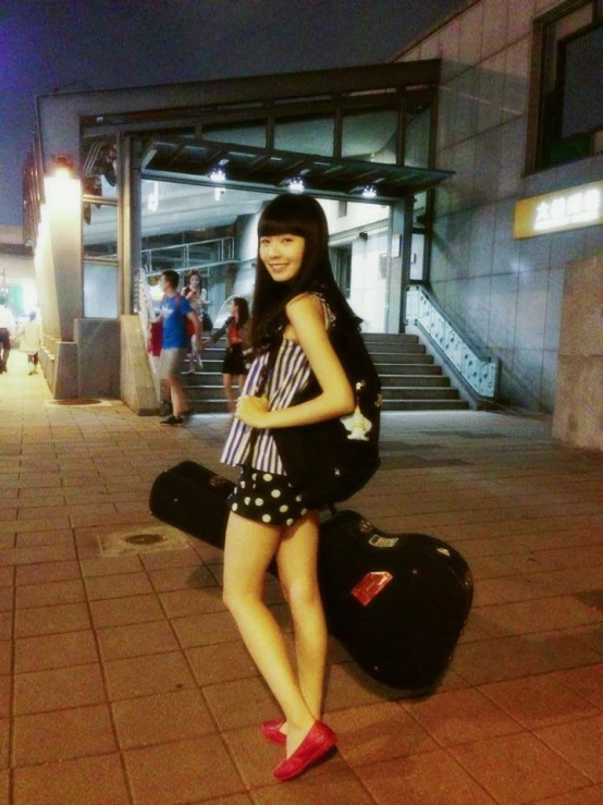 girl in short black and white dress standing by luggage