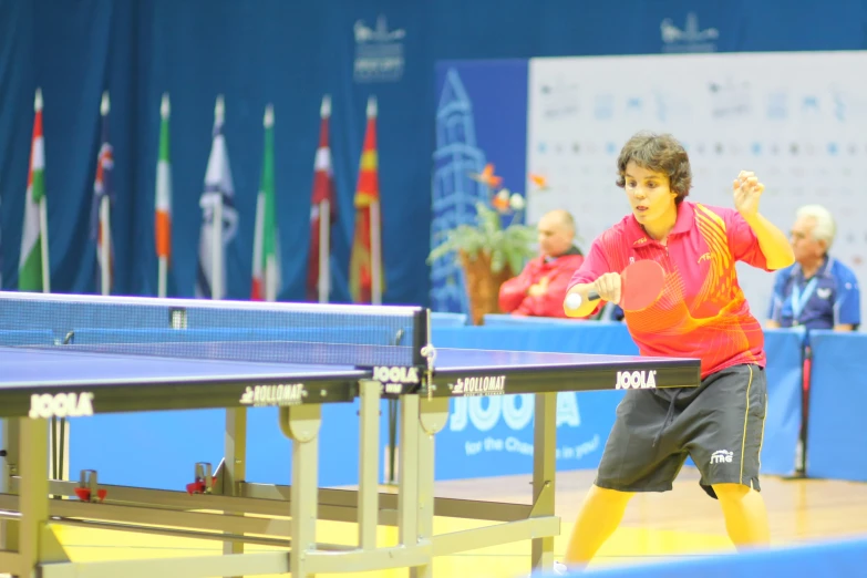 man playing table tennis at indoor event with audience watching