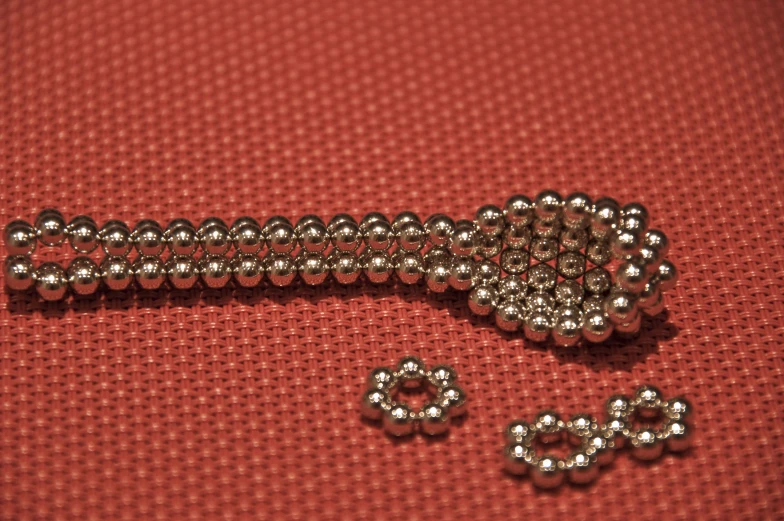 the metal beads are laying on the red cloth