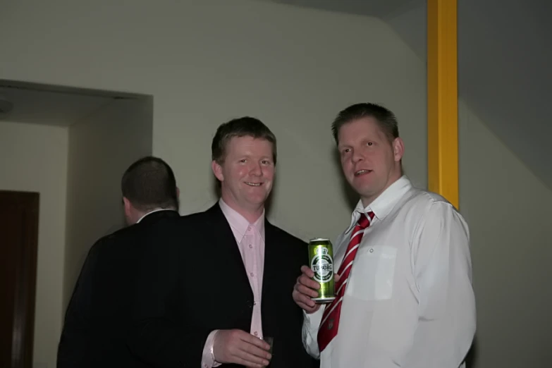 two men smiling while one holds a green beer