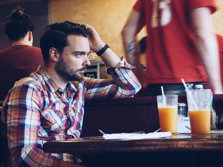 a man is holding his head while sitting at a table