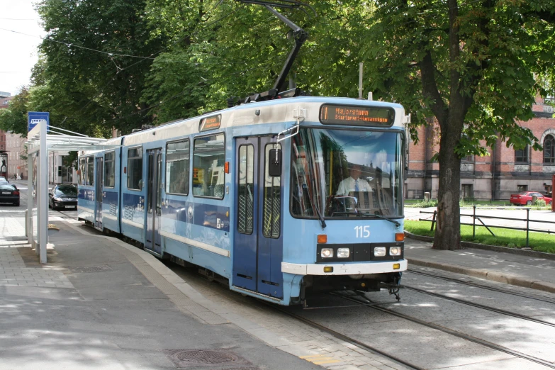 blue trolly car pulling passengers along the tracks in a city