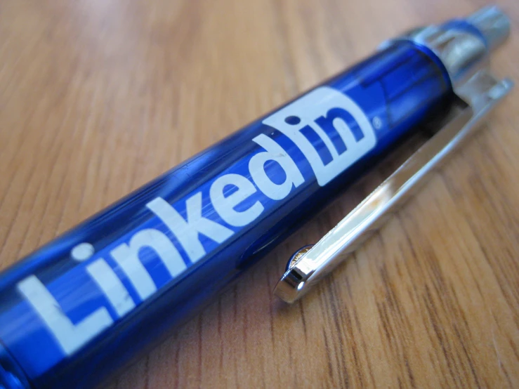 a blue and silver pen laying on top of a wooden table