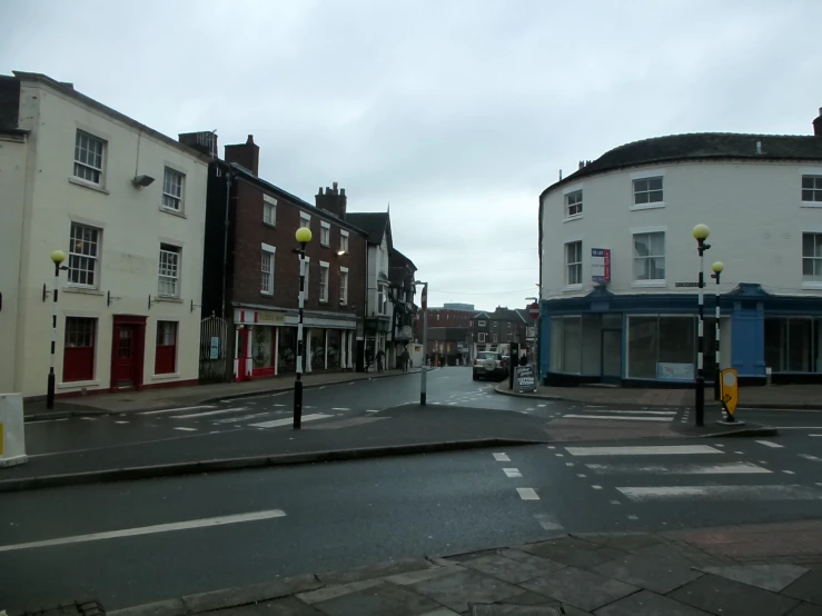 a road with buildings in the background during a rain soaked day