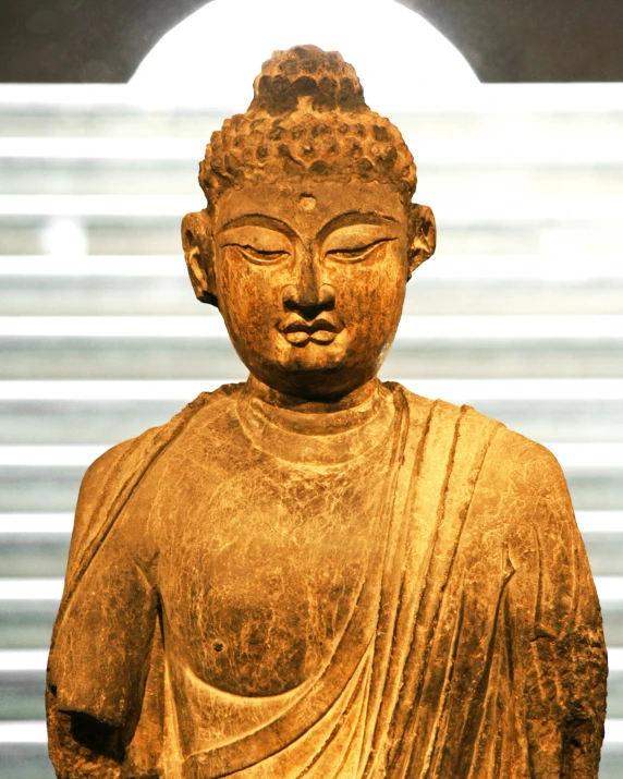 a gold buddha statue is shown against a window