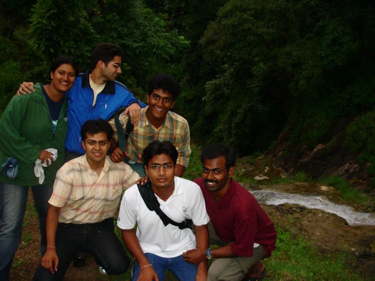 a group of young men and women pose together in the woods