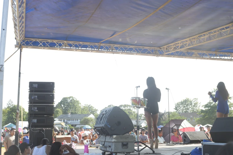 a band playing on stage at a festival with many people