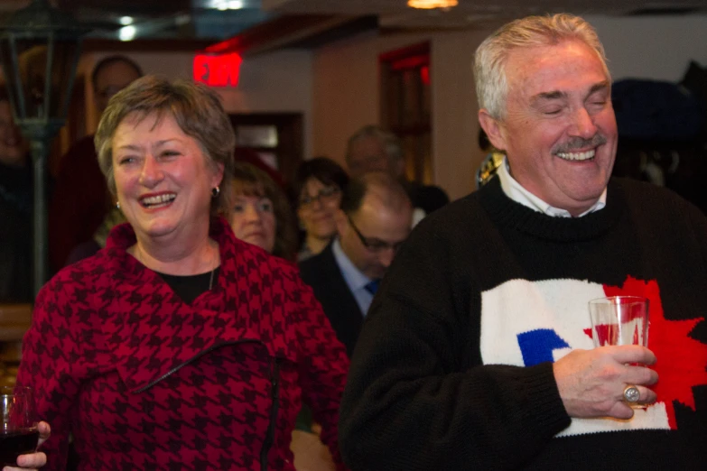 a man and woman smile and hold glasses of wine