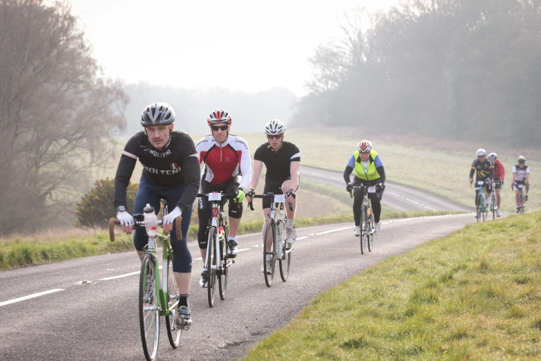 several cyclists traveling down a road on bicycles