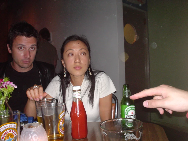 two people in front of a table with bottles of alcohol