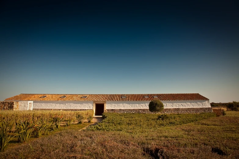 a farm house with an open roof sitting in the middle of a field