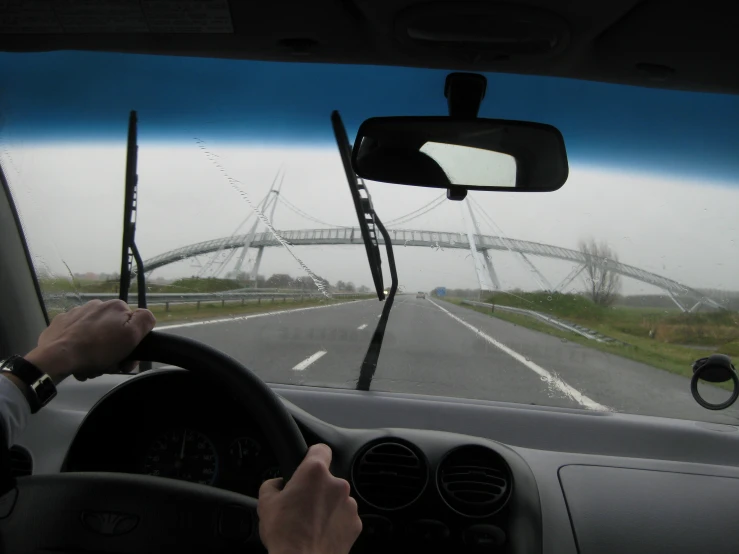 man in car driving over bridge seen from inside