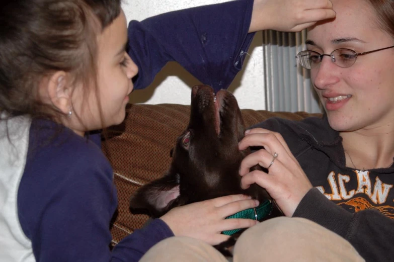 a lady sitting on a couch and petting the nose of another woman