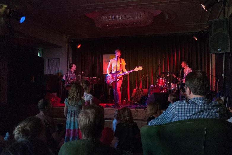 a man with a guitar on stage, on a stage audience