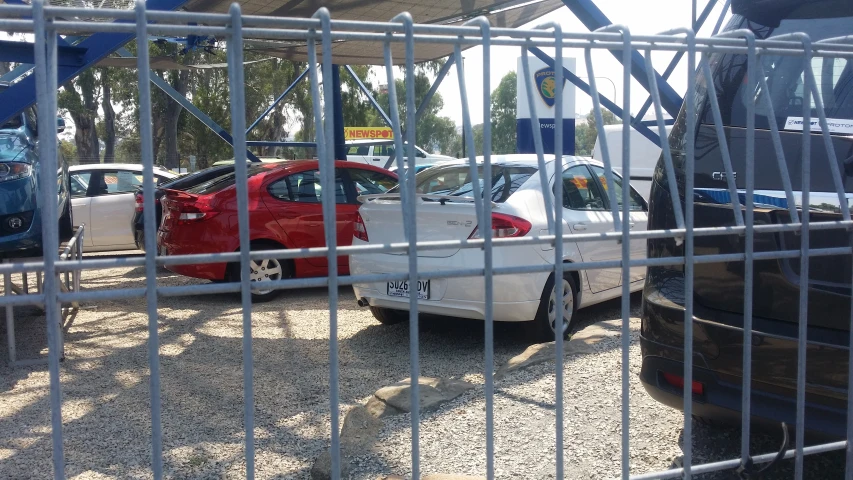 a white car is parked on a lot behind a fence