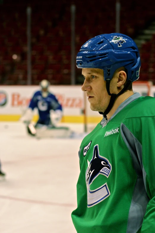 a man standing on a ice rink in front of an ice hockey goalie