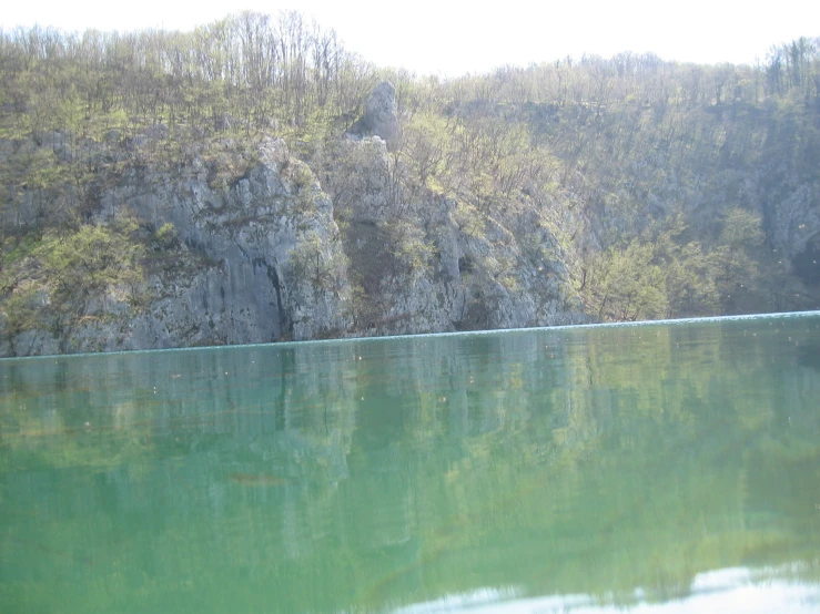a beautiful green lake surrounded by trees and cliffs