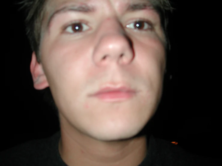 a man with blonde hair stares ahead while wearing a black shirt