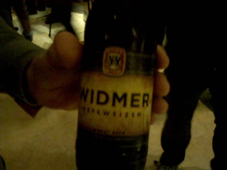 a man holding up a beer bottle with the word widmer