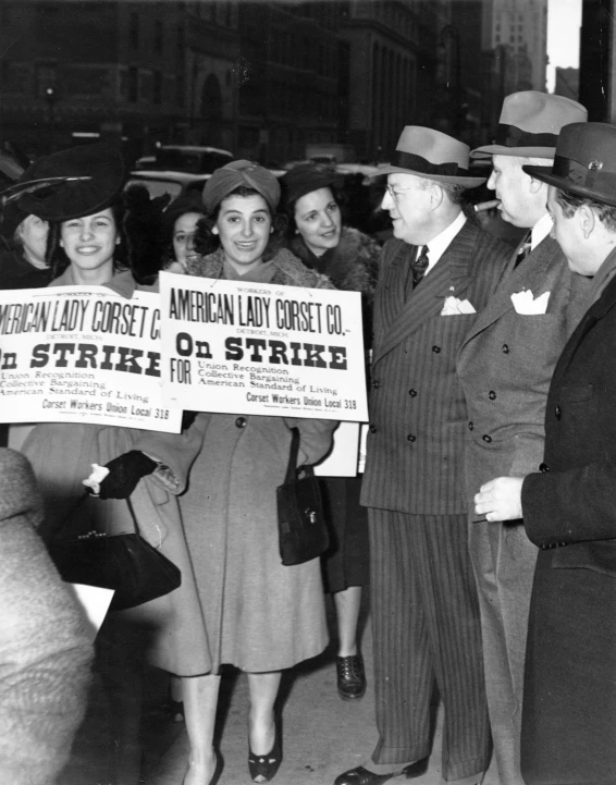 the woman is handing a large banner to the man in black suit