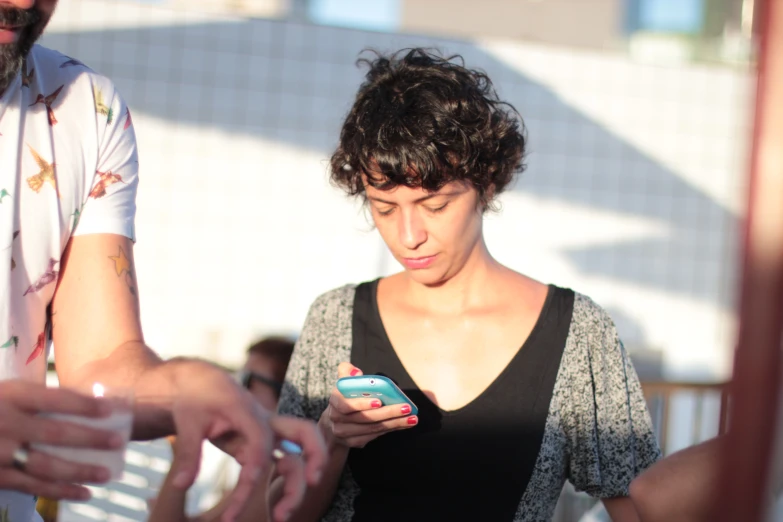 a woman standing in front of a man holding a cell phone