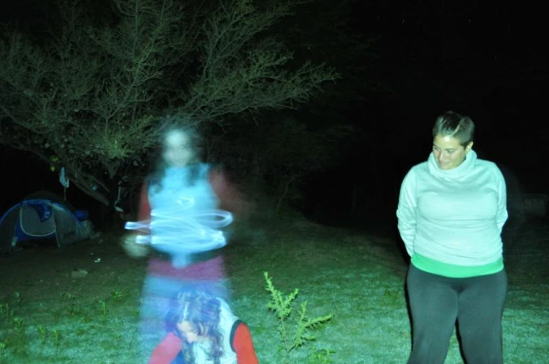 a girl watches a frisbee thrown at night