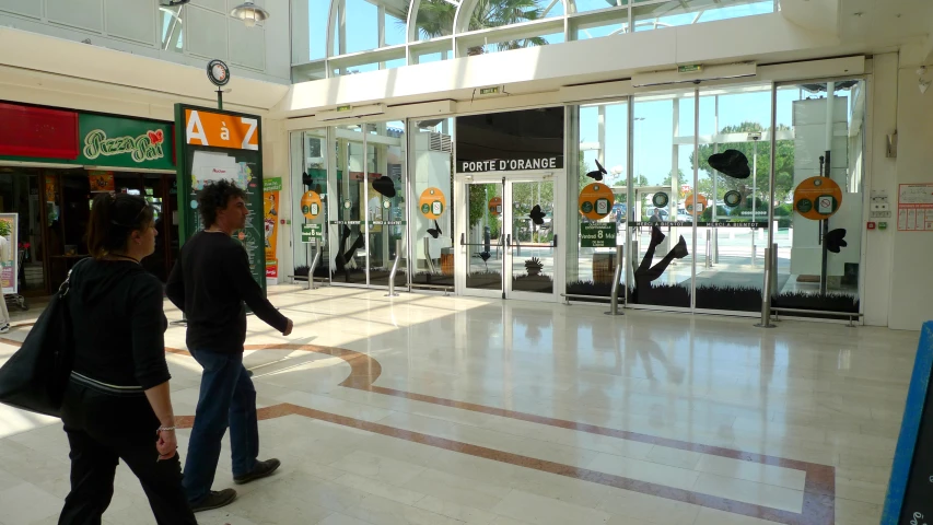 two people walking inside a building toward the entrance