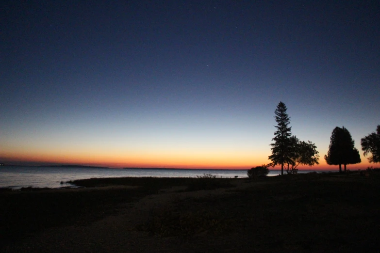 a sunset view of trees and water with a beach nearby