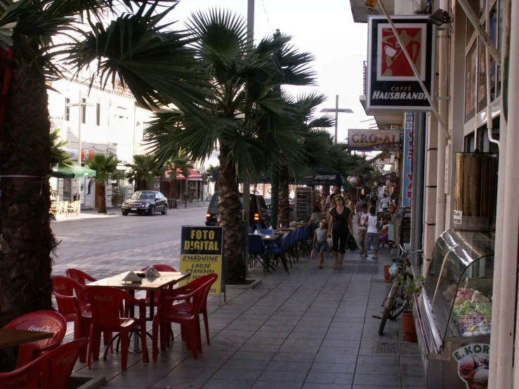 there are people walking down the sidewalk in front of shops