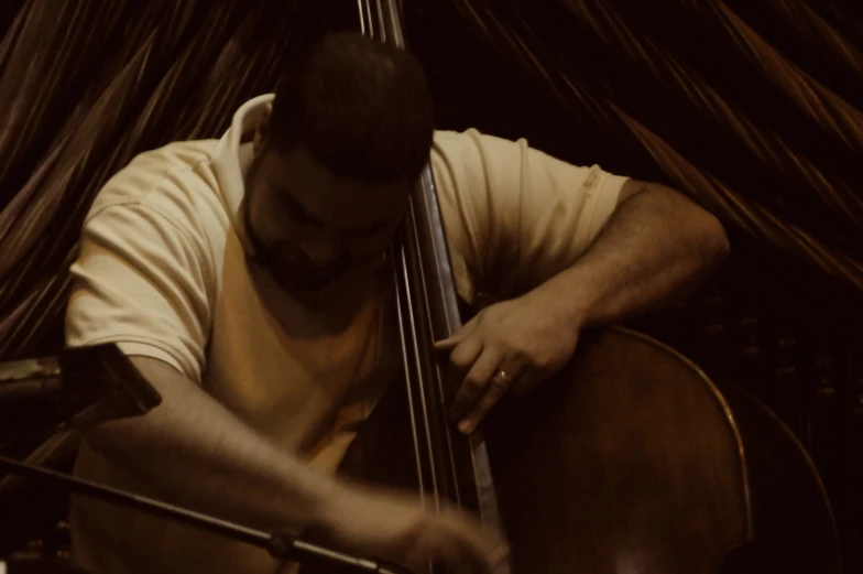 a man sitting down playing the cello