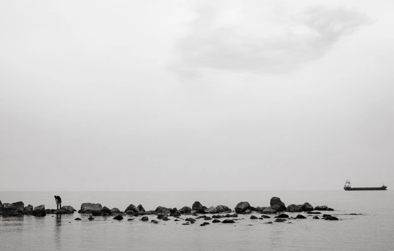 the two people are standing on rocks looking out at the water