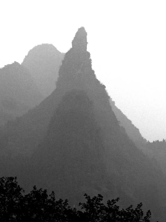 a silhouette of a mountain side in the fog