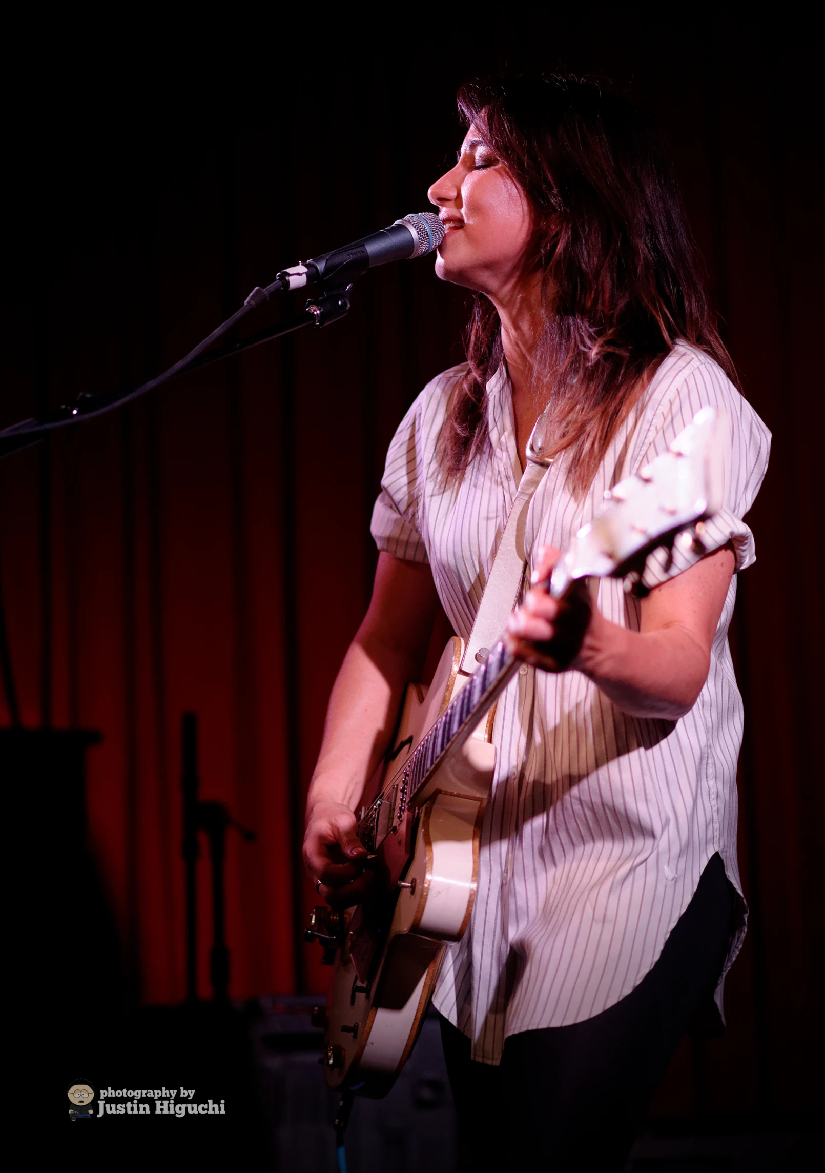 a woman with a guitar at the microphone