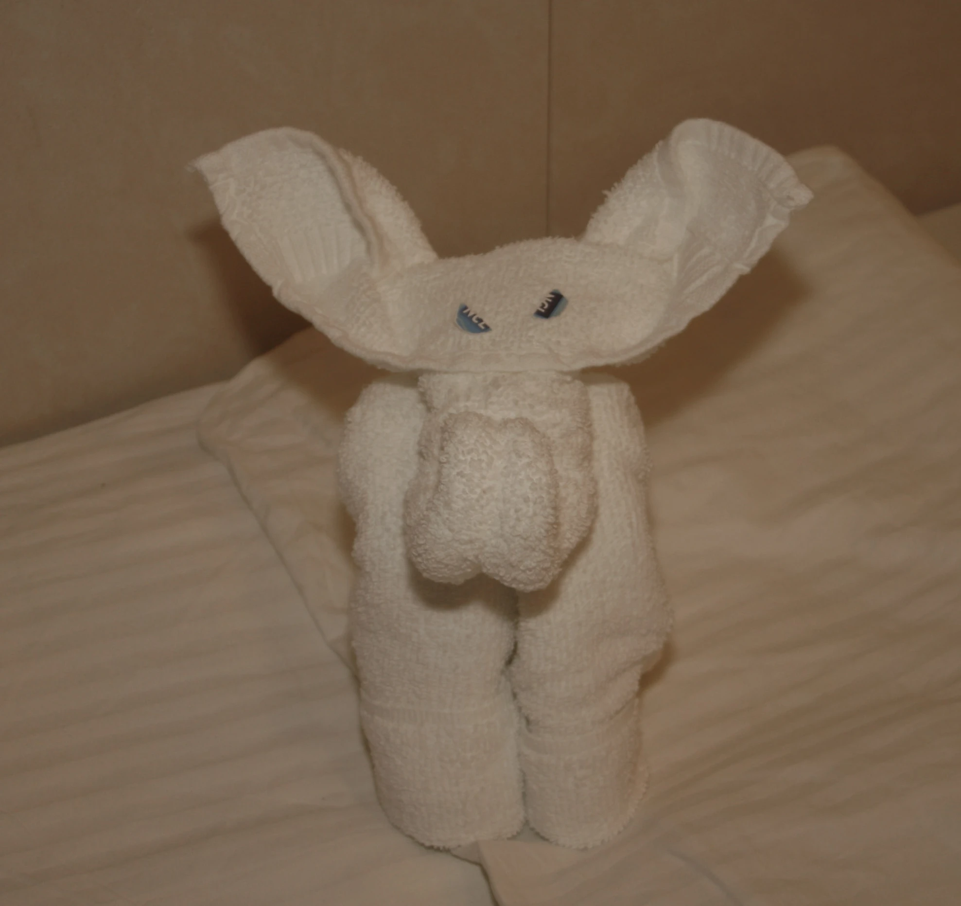 a white toy animal made to look like an elephant sitting on top of a bed