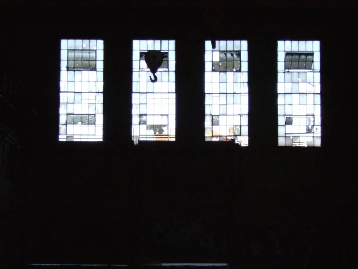 the silhouette of three open windows that are in a dark room