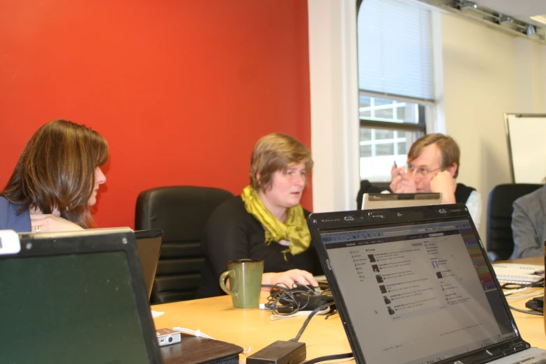 three people in an office with two women on the side of a computer