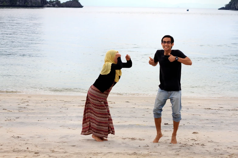 a man and woman dance on a beach near the ocean