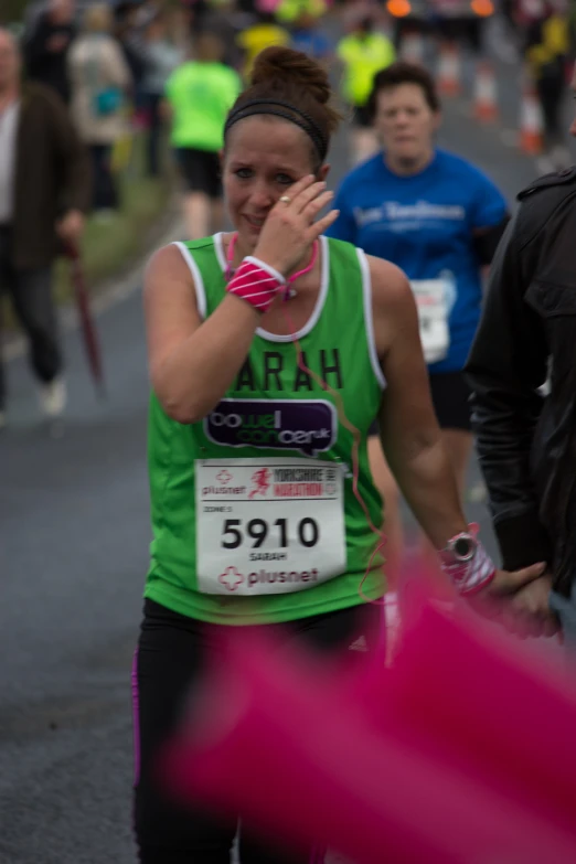 the woman is running in a marathon wearing her green shirt