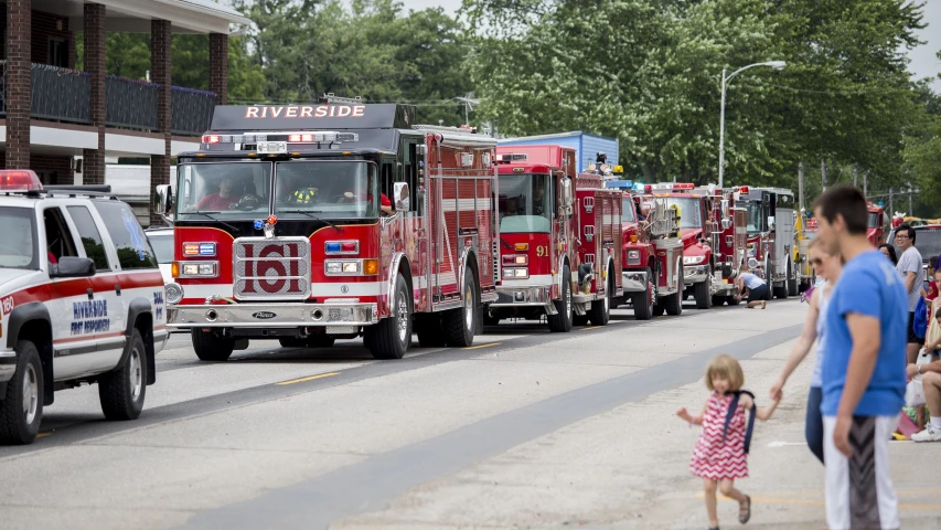 some fire trucks are parked on a street while a  walks by