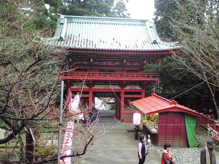 a person walks down a pathway in front of an oriental shrine