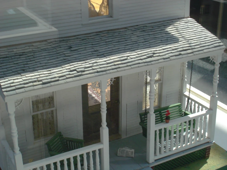 a small white house with green bench outside