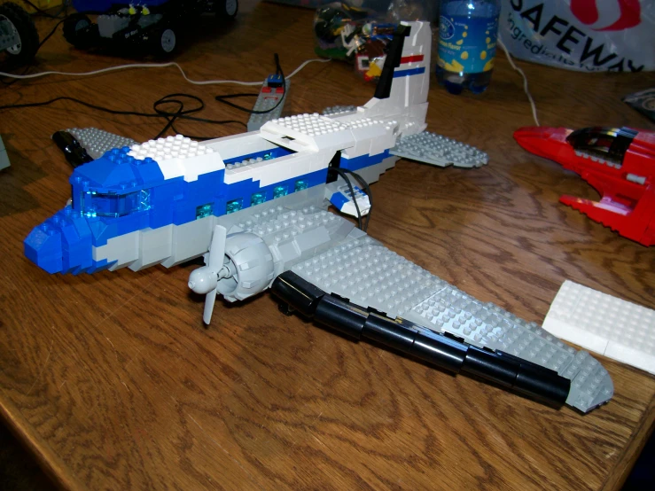 lego airplane on table near toy rocket and water bottle