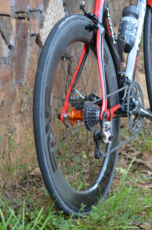 an orange bicycle leaning against a brick wall