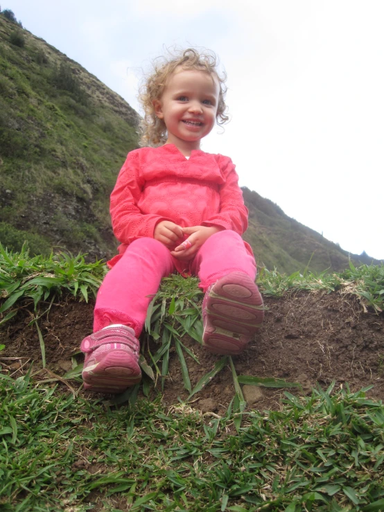 a child sitting on top of a lush green hillside