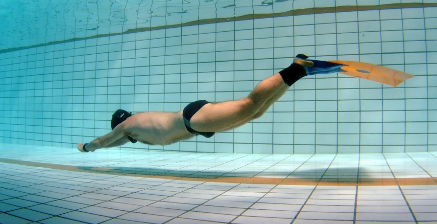 man floating in an indoor swimming pool with an umbrella