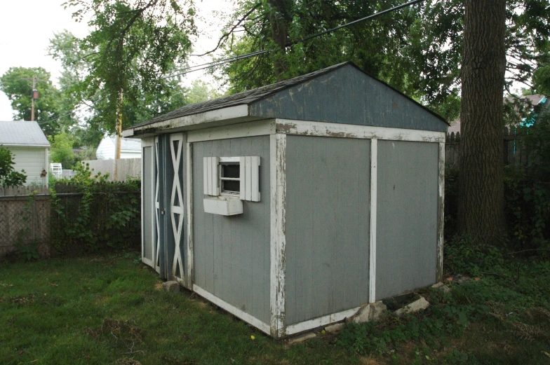 an old shed sitting in the yard with a window on one side