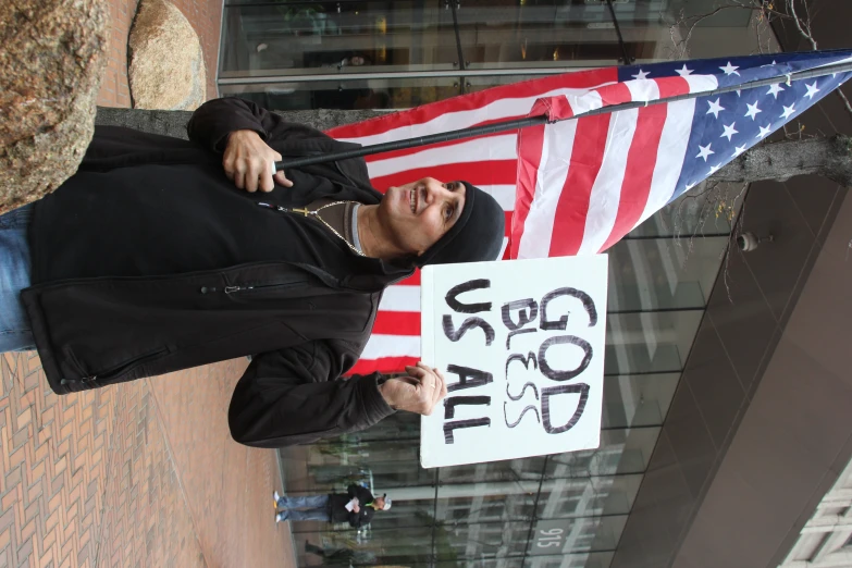 there is a man holding up an american flag and a sign