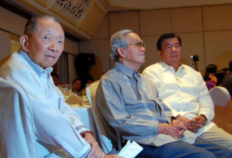 two men in suits and ties are looking away from the camera while sitting down