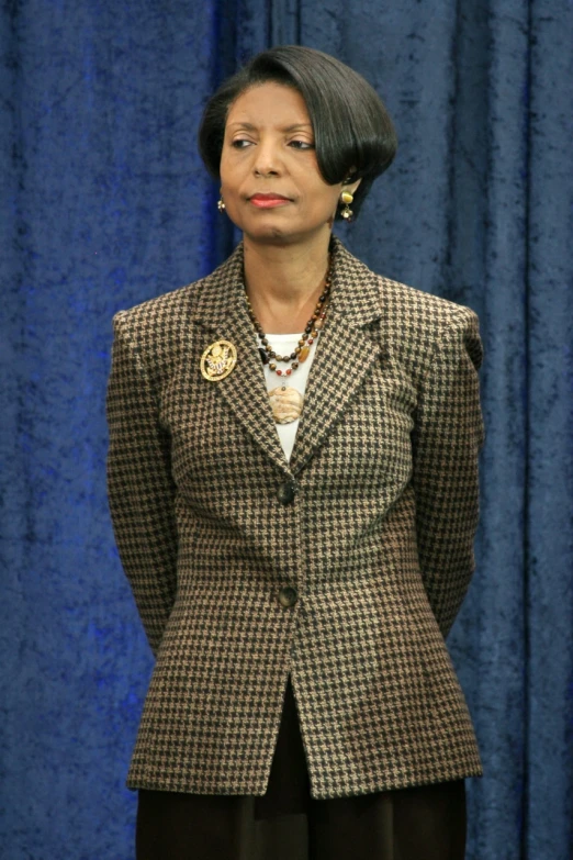 an african american woman in a suit and gold brooche