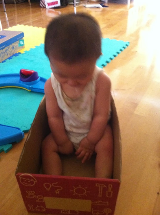 a child sitting inside a box playing with an electronic device